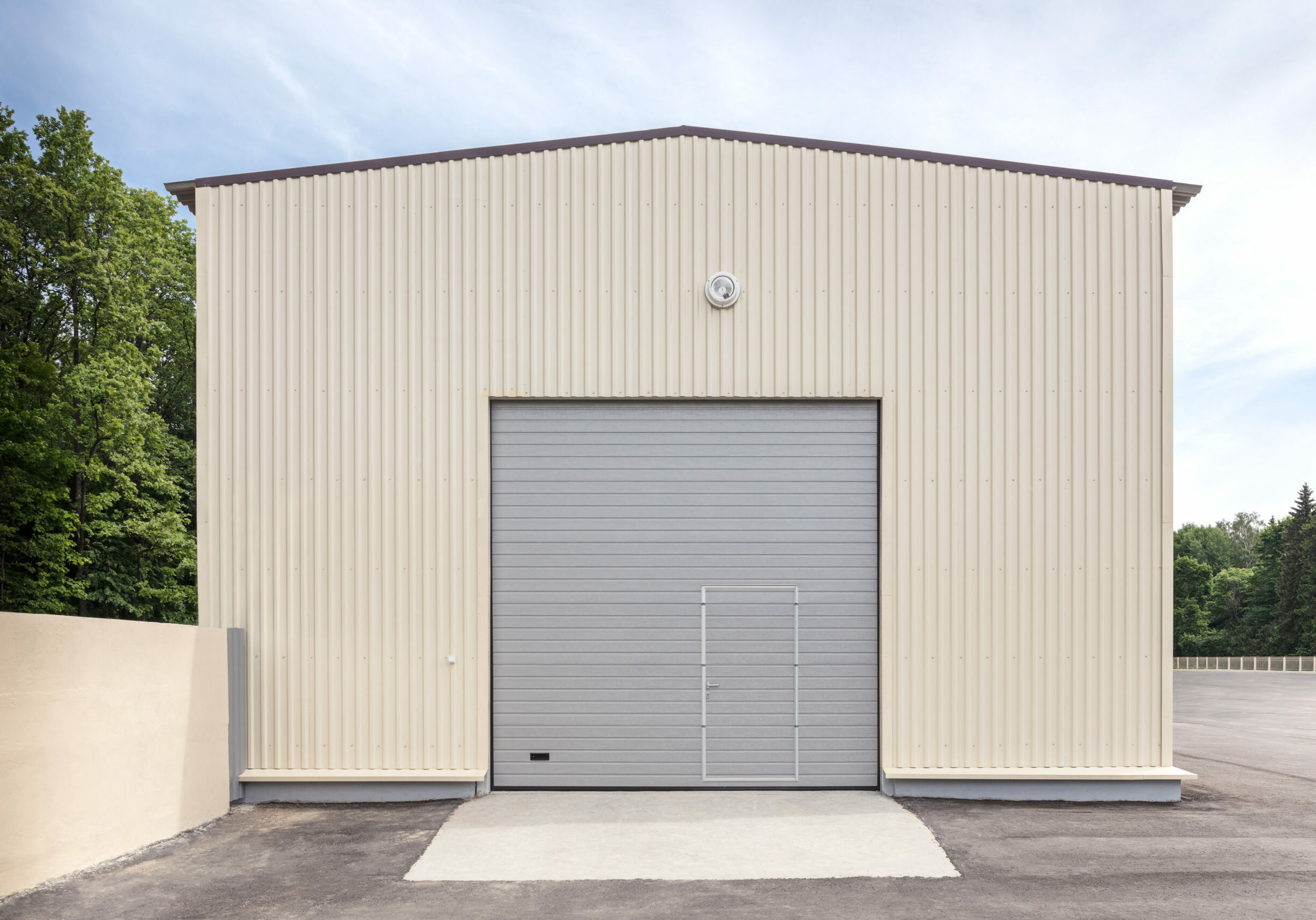 facade of industrial storehouse with closed gray metal gate and door